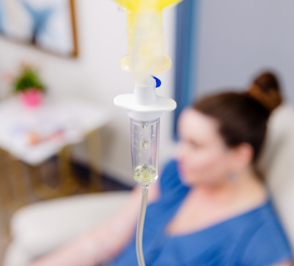 A woman sits and relaxes as she receives a treatment with NAD+ in Lenexa through an IV drip.
