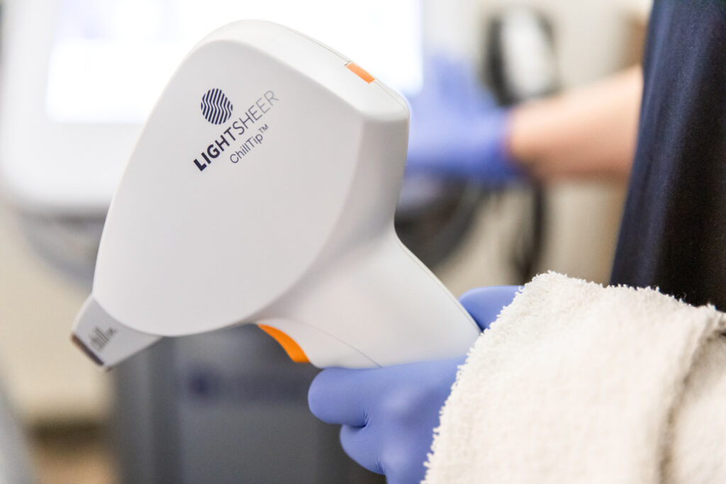 A provider at Physician Aesthetic Specialists holds up a device for laser hair removal near Overland Park.