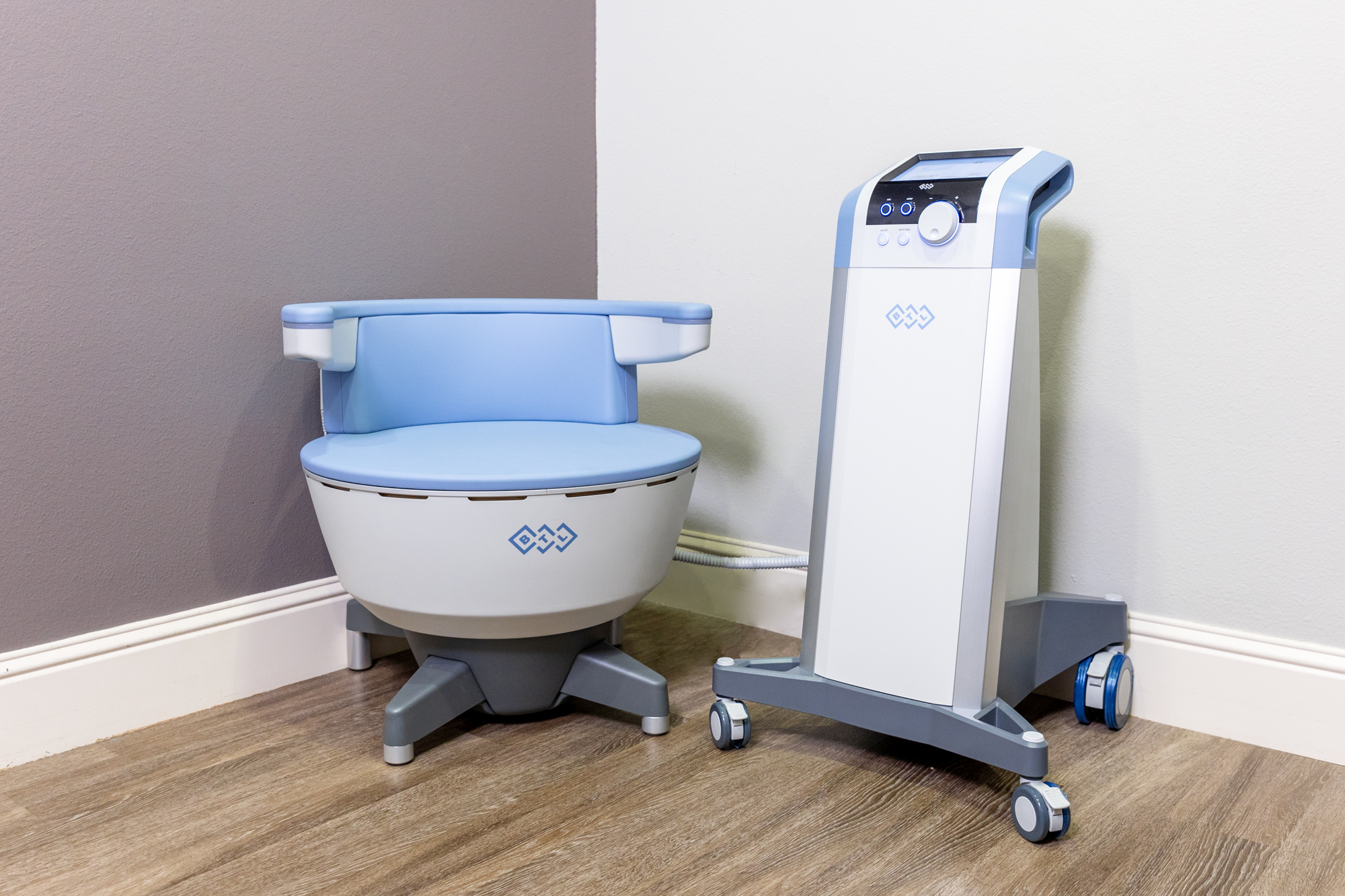 An Emsella chair and control center in the corner of a treatment room. It provides pelvic floor therapy as part of sexual wellness for men in Lenexa.
