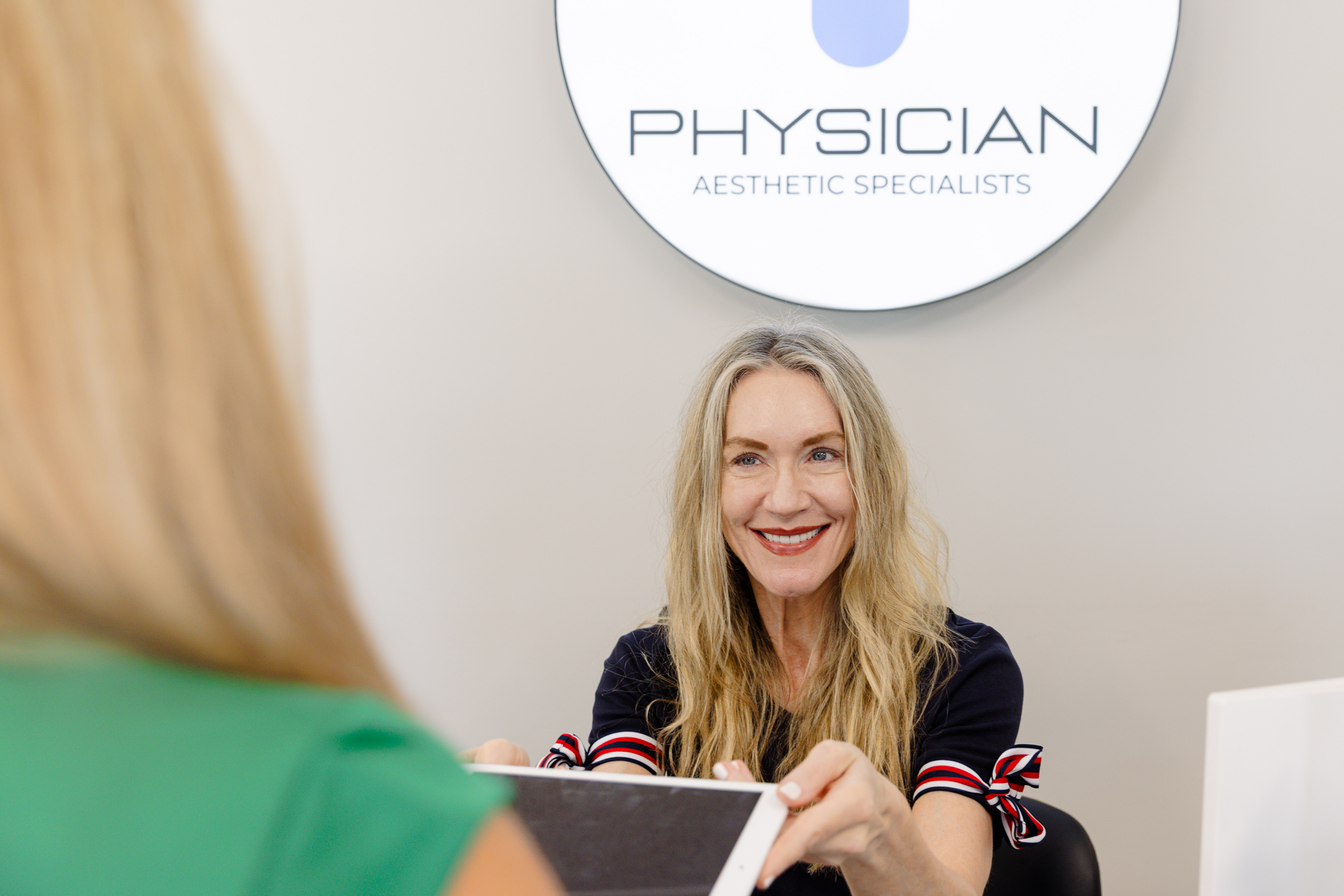 A patient talks with a provider with long blonde hair about hair restoration near Overland Park